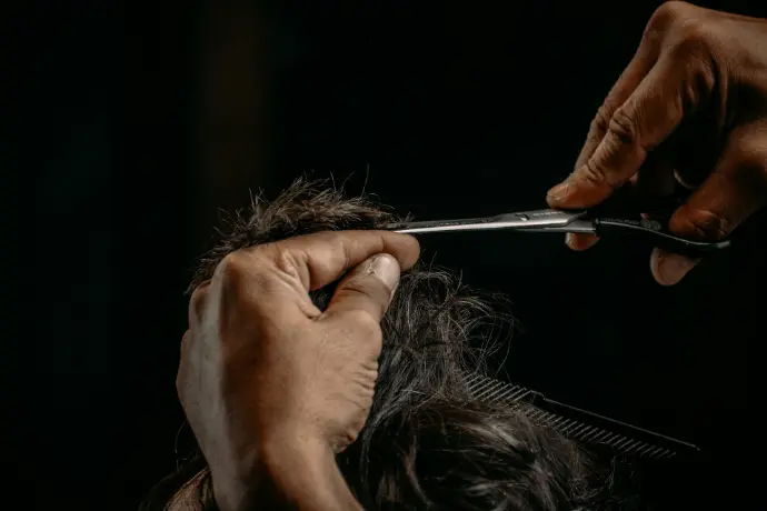 a person cutting a woman's hair with scissors